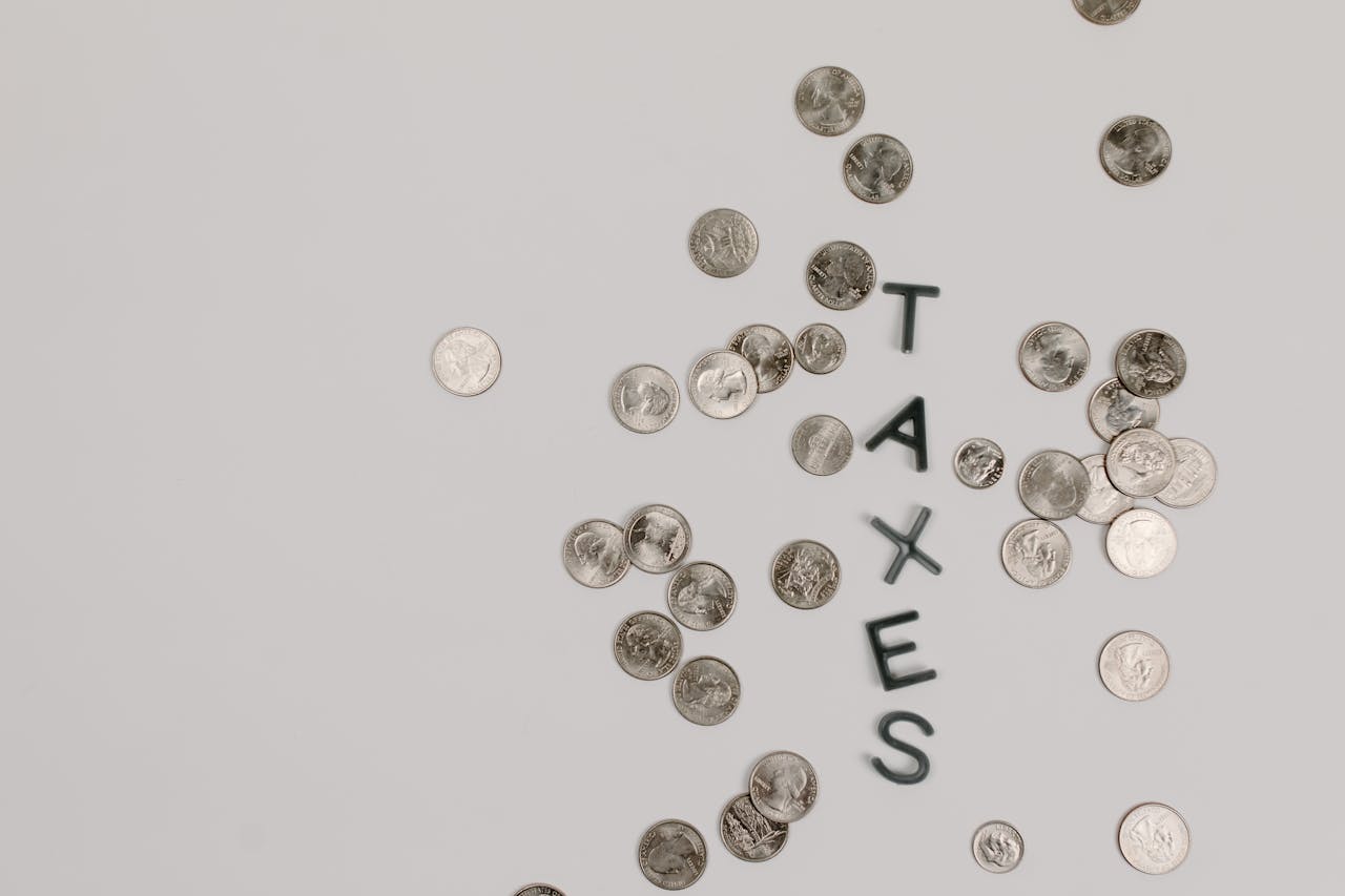 testimonials-img Scattered coins forming the word TAXES on a white surface, symbolizing financial concepts.